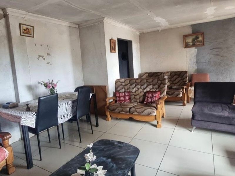 A living room area featuring ceramic floor tiles and coved ceilings, currently requiring significant cosmetic updates to the wall and ceiling finishes.