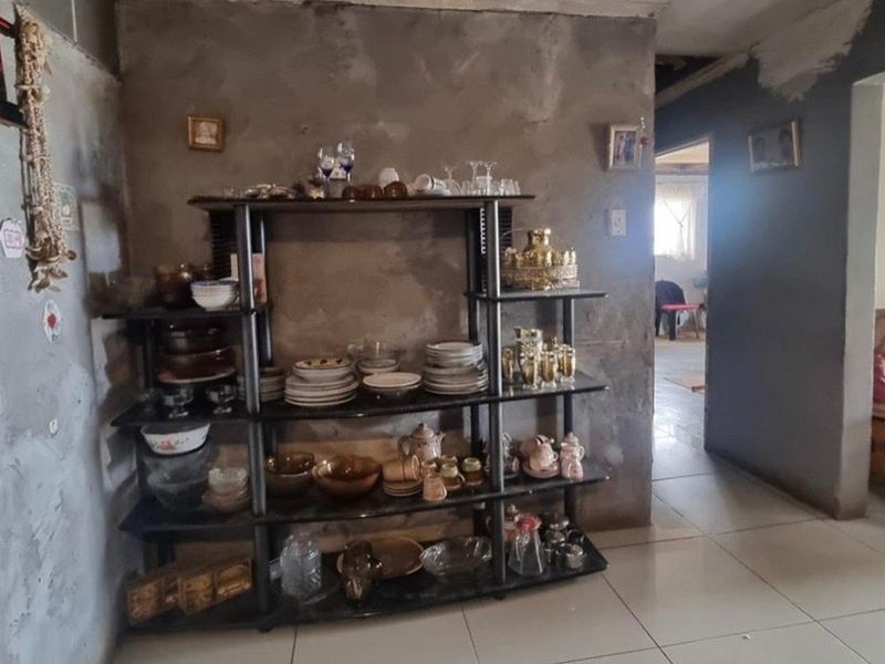 Living area featuring tiled flooring and unfinished cement walls, requiring cosmetic updates and finishing to improve the overall aesthetic and condition.