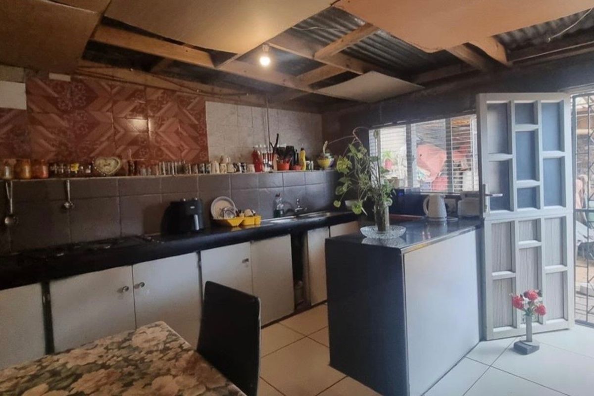 A functional kitchen featuring built-in cabinetry, tiled backsplash, and direct access to an outdoor area through a security gate.