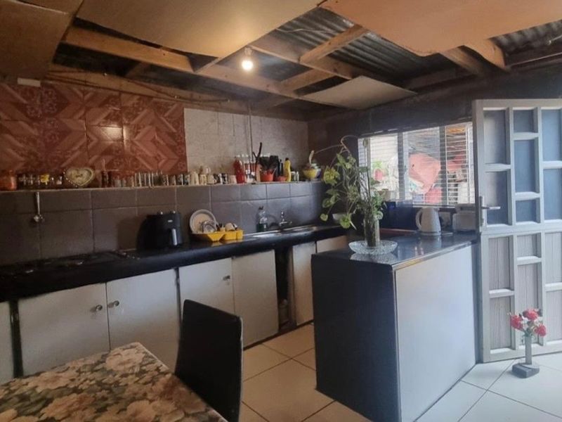 A functional kitchen featuring built-in cabinetry, tiled backsplash, and direct access to an outdoor area through a security gate.