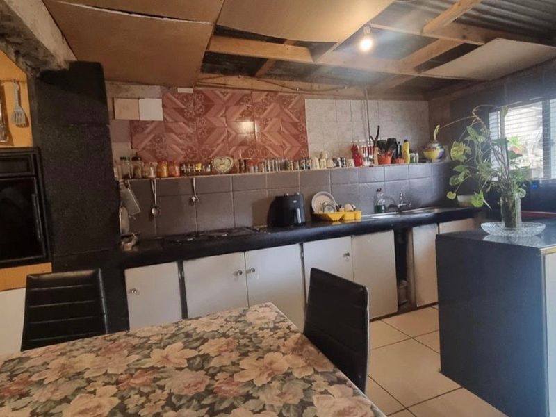 A kitchen featuring built-in cabinetry, a hob, and an oven, with an unfinished ceiling requiring repair and modernization.