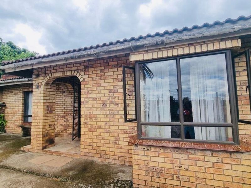 A traditional face brick house exterior featuring an arched entrance and a prominent bay window with a tiled roof.