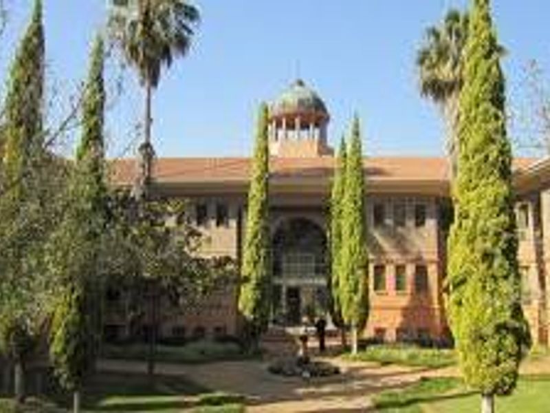 A professional exterior view of a commercial building featuring a central cupola, symmetrical facade, and well-maintained landscaped gardens in the foreground.