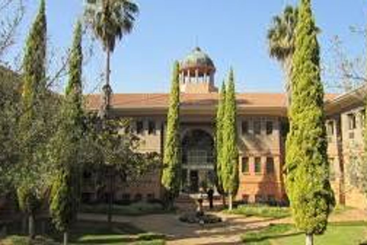 A professional exterior view of a commercial building featuring a central cupola, symmetrical facade, and well-maintained landscaped gardens in the foreground.