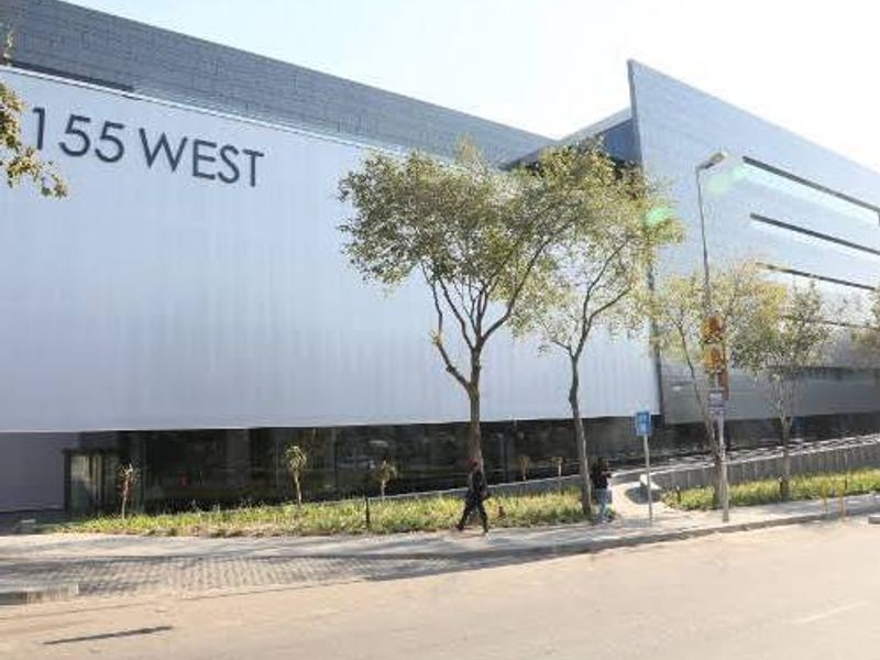 Modern commercial office building facade featuring sleek metal cladding and prominent street-level signage at 155 West.