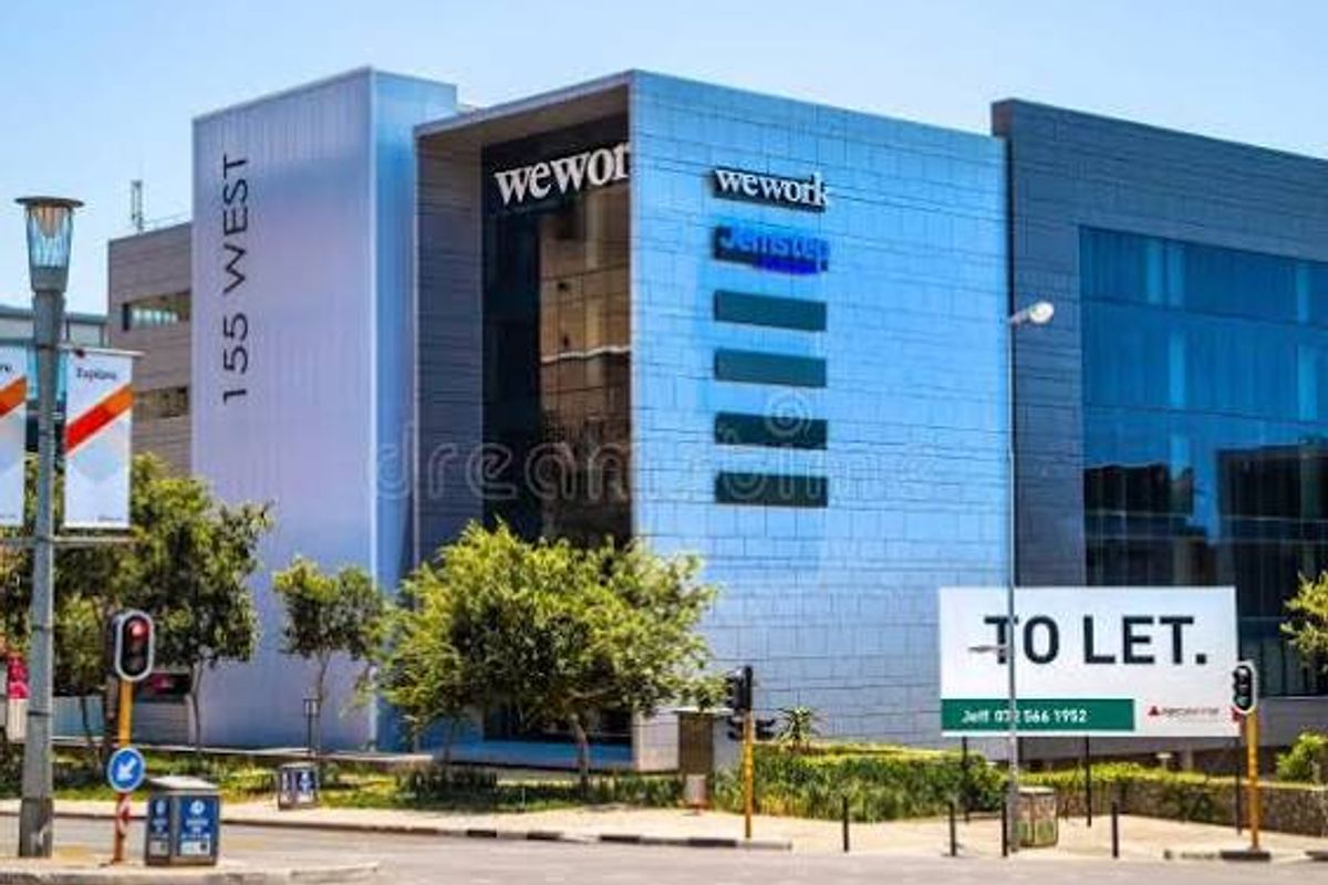 Front exterior view of a modern commercial office building featuring glass facades, metal cladding, and prominent signage.