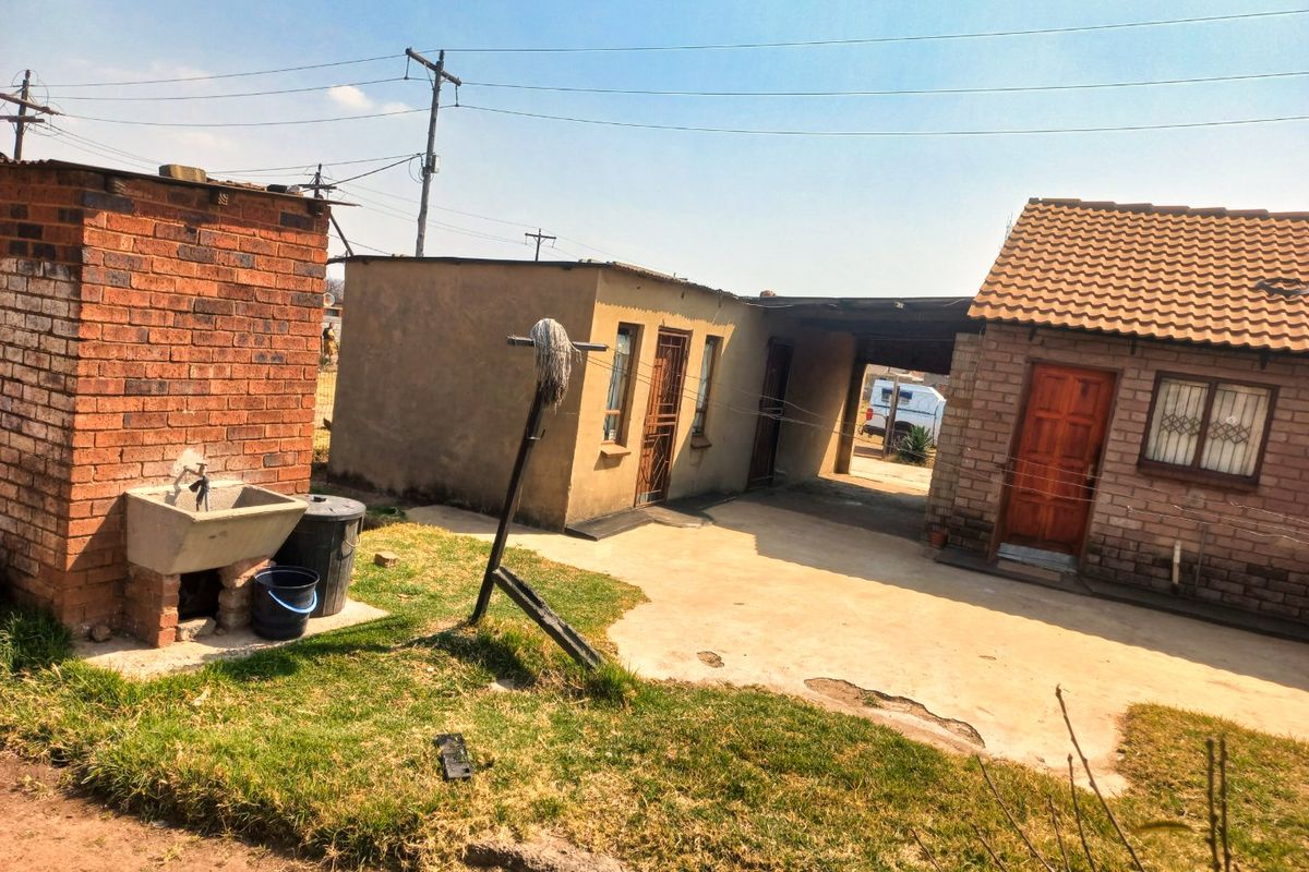 Rear exterior view of the property featuring a concrete patio, brick utility structure with a wash basin, and access to the main dwelling.