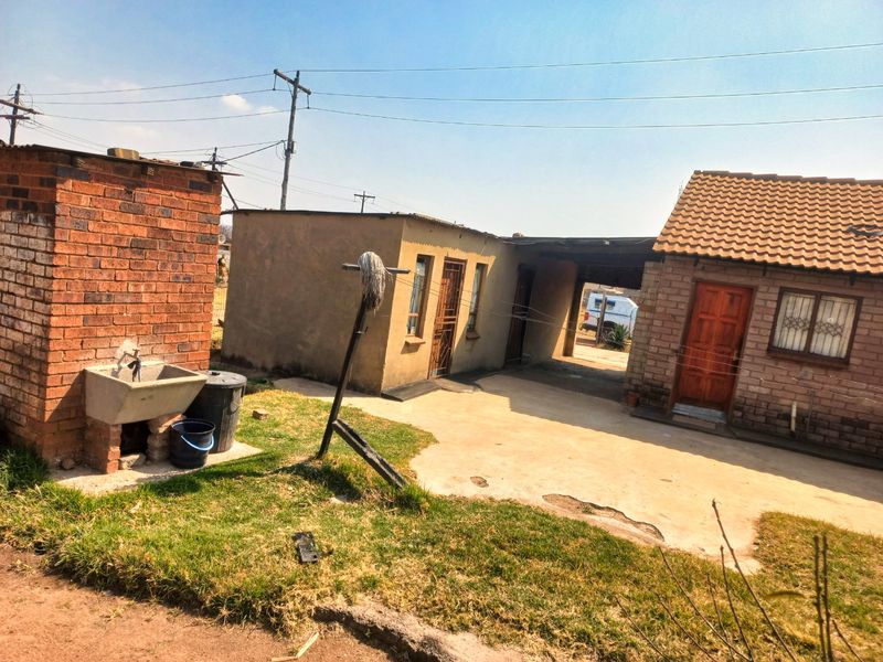 Rear exterior view of the property featuring a concrete patio, brick utility structure with a wash basin, and access to the main dwelling.