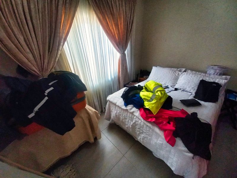 A bedroom featuring tiled flooring and window treatments, offering a functional space ready for personalization.
