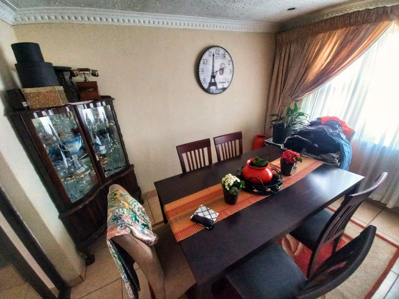 A dining room featuring tiled flooring and decorative ceiling cornicing, currently showing signs of ceiling staining.