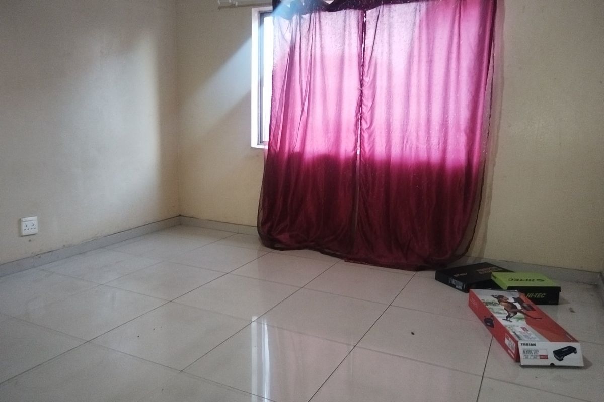 An empty bedroom featuring tiled flooring and a window with curtains, providing a blank canvas for personalization.