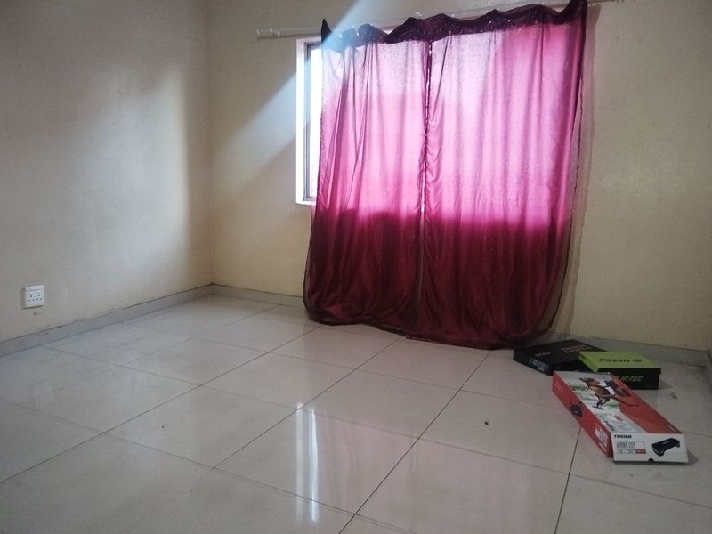 An empty bedroom featuring tiled flooring and a window with curtains, providing a blank canvas for personalization.