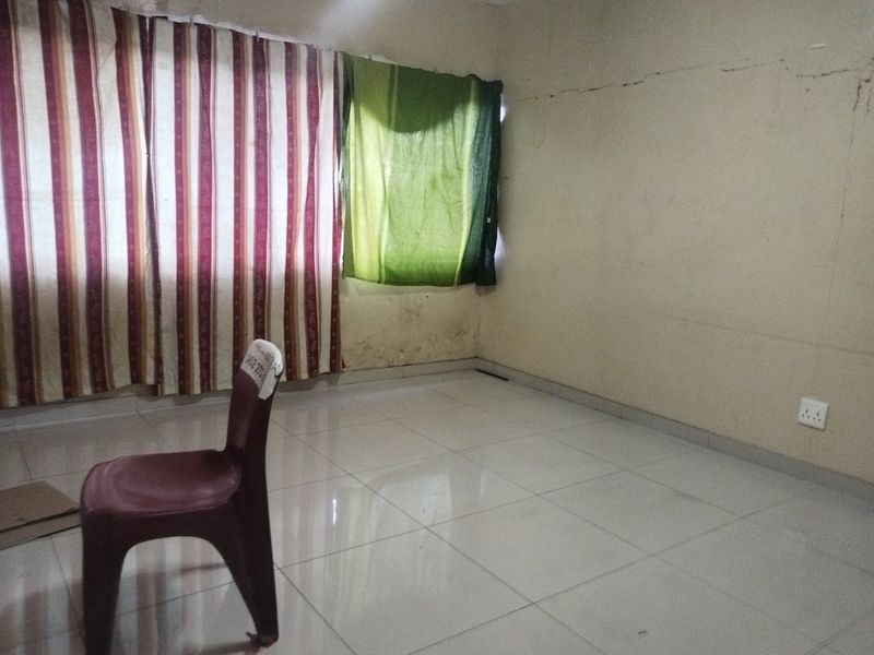 An empty bedroom featuring tiled flooring and visible wall damage, requiring maintenance and cosmetic updates.