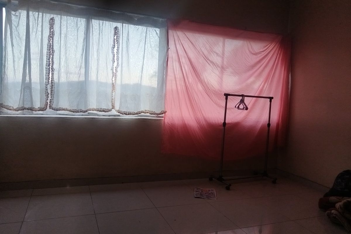 A vacant bedroom featuring tiled flooring and a large window, offering a blank canvas for potential interior design and renovation.