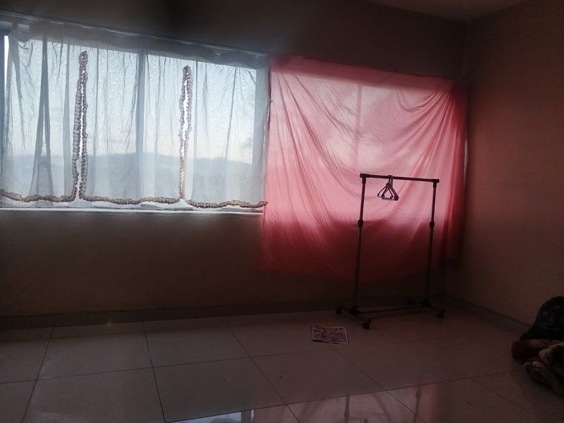 A vacant bedroom featuring tiled flooring and a large window, offering a blank canvas for potential interior design and renovation.