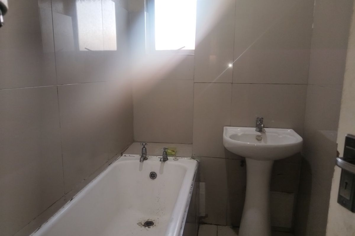 A compact bathroom featuring a pedestal basin and a standard bathtub with full-height wall tiling.