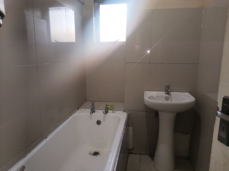 A compact bathroom featuring a pedestal basin and a standard bathtub with full-height wall tiling.