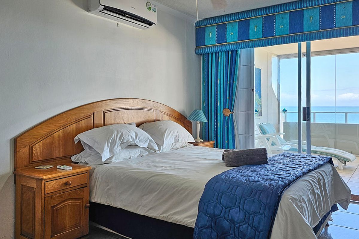 A bedroom featuring tiled flooring, a split-system air conditioner, and direct access to a balcony with ocean views.