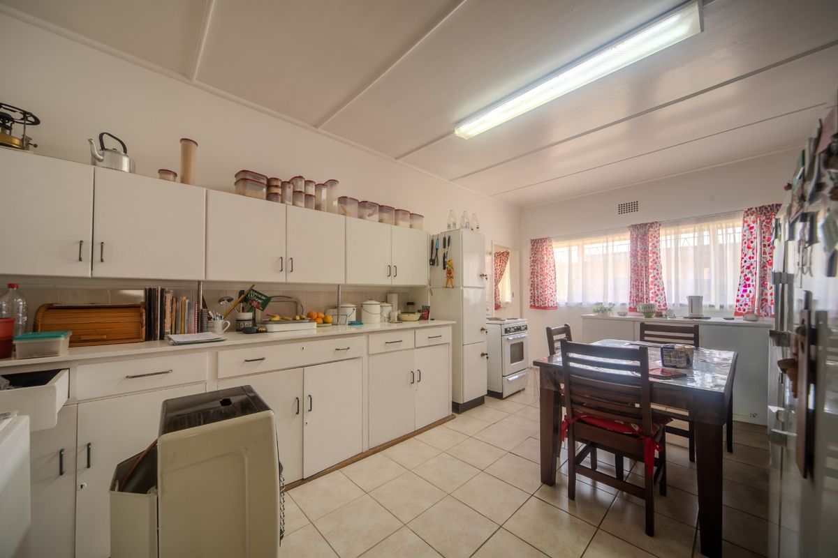 A functional kitchen featuring white built-in cabinetry, tiled flooring, and a freestanding oven, offering a classic layout with ample storage space.