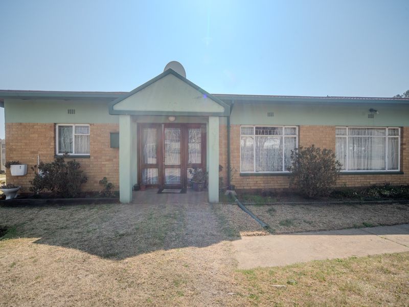 Front elevation of a single-story brick house featuring a covered entrance porch, security bars on windows, and a concrete walkway leading to the front door.