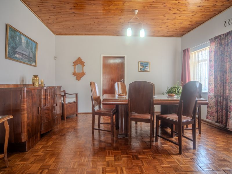A traditional dining room featuring warm parquet flooring and a timber-clad ceiling, offering a classic aesthetic with potential for modern updates.