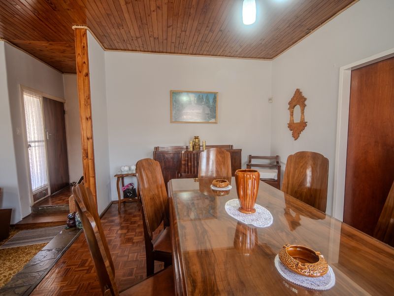 A traditional dining room featuring warm timber ceiling paneling and classic parquet flooring, providing a cozy and established atmosphere.