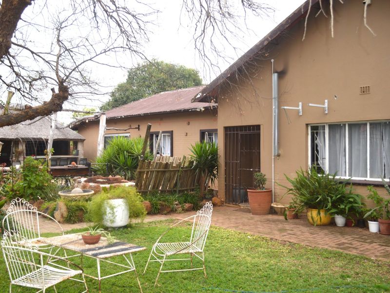 Rear view of the property featuring a brick-paved patio area, established garden, and a detached lapa structure.