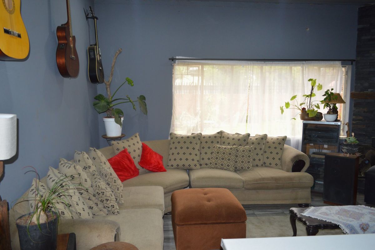 A living room featuring dark grey walls, a large window with sheer curtains, and a stone feature wall element.