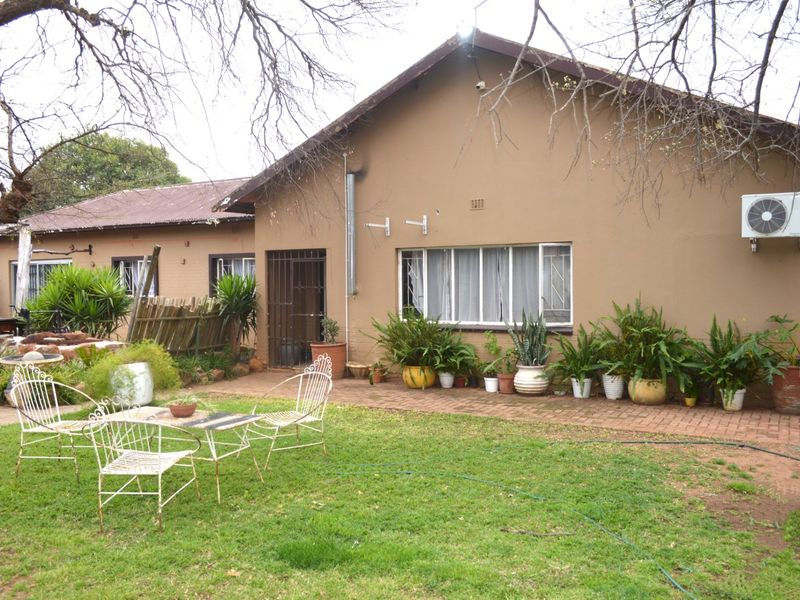 Rear view of the house featuring a paved patio area, lawn, and exterior wall with an installed air conditioning unit.