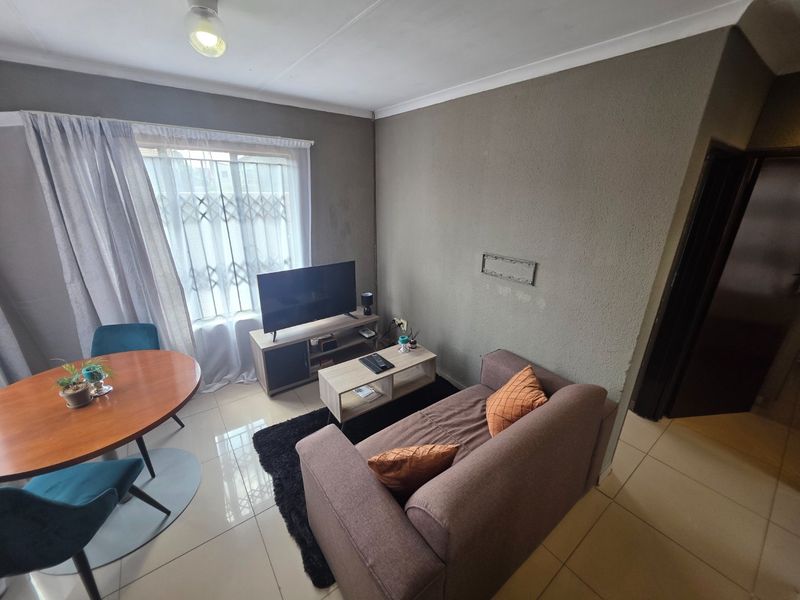 Open-plan living and dining area featuring tiled flooring and neutral wall finishes, providing a functional space for daily living.