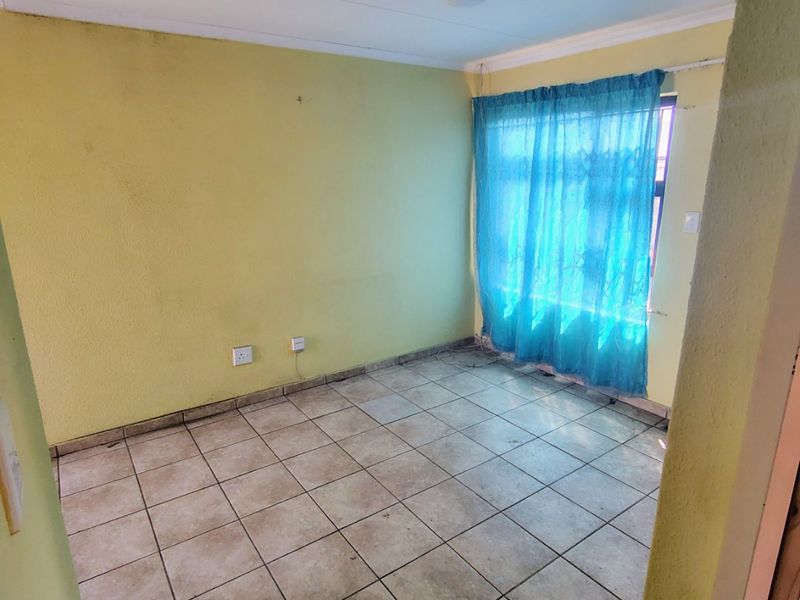 An empty bedroom featuring ceramic tiled flooring and yellow painted walls, offering a blank canvas for renovation or interior design updates.