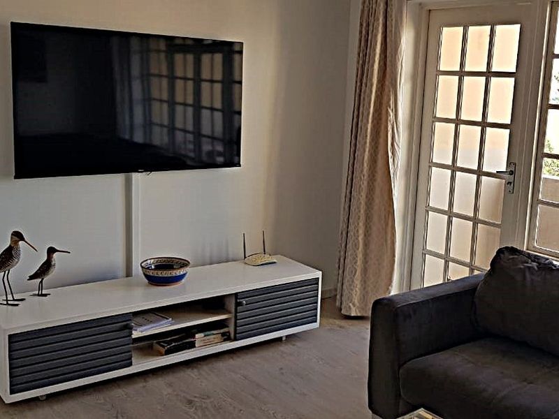 A living room area featuring laminate flooring and a glass-paneled french door leading to an outdoor space.