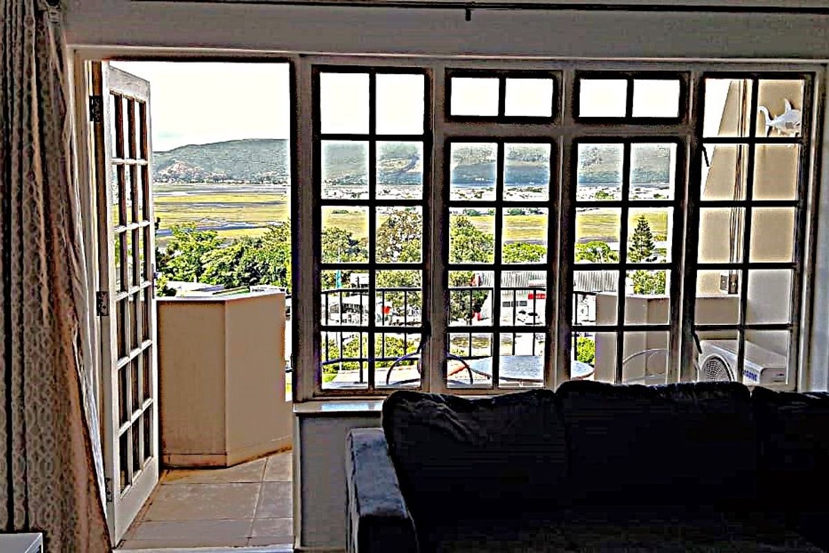 Living room featuring large grid-pattern windows and a french door opening onto a balcony with scenic landscape views.