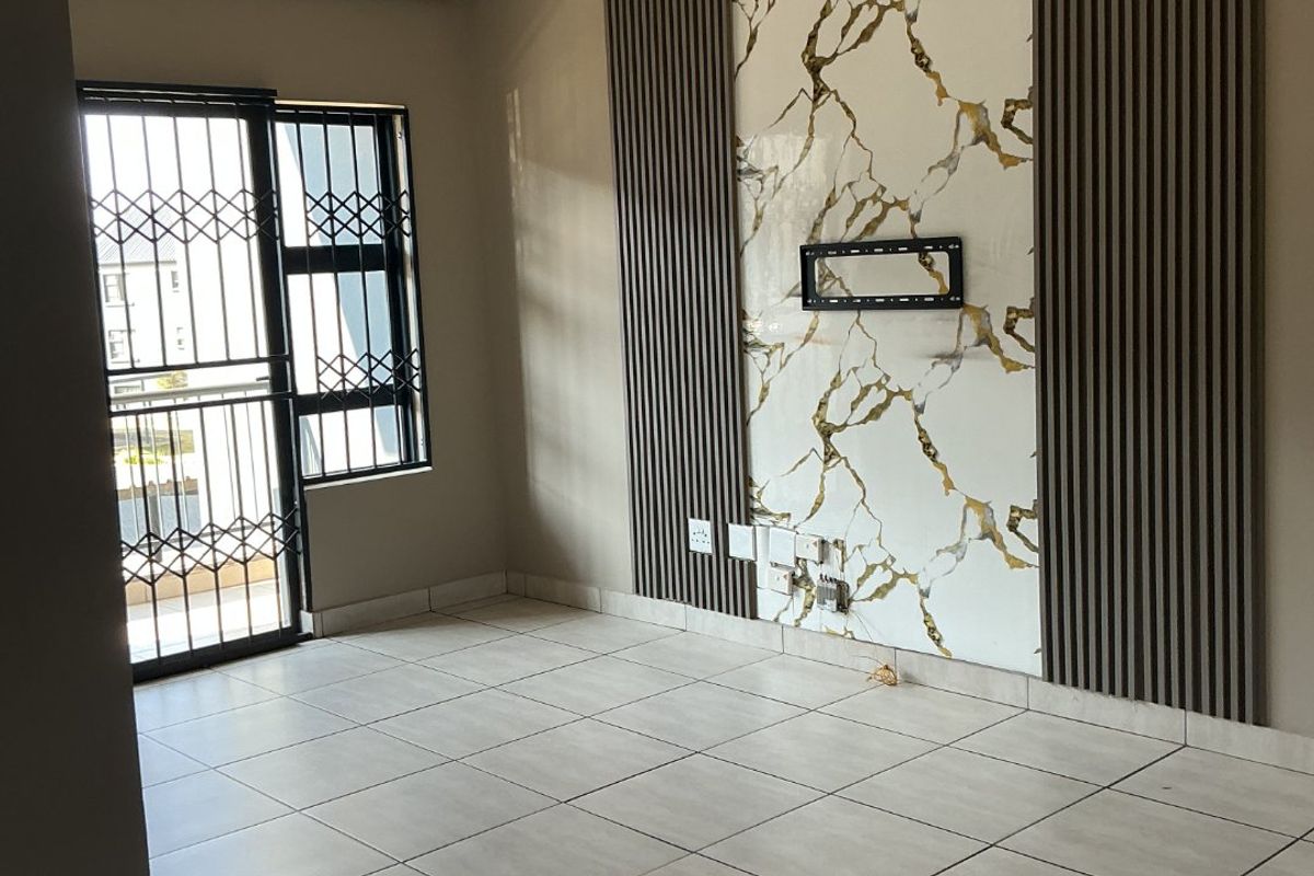 A bright, empty living room featuring modern marble-effect wall paneling, vertical timber slats, tiled flooring, and a secure entrance door.