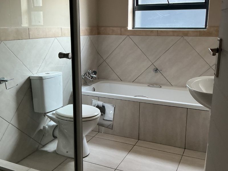A functional bathroom featuring a bathtub, separate shower enclosure, pedestal basin, and neutral tiled finishes throughout.