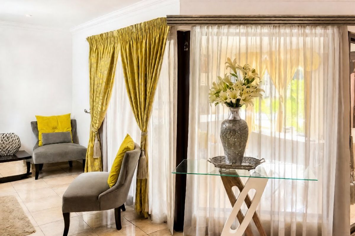 A bright living area featuring tiled flooring, decorative ceiling cornicing, and large glass sliding doors that provide ample natural light.