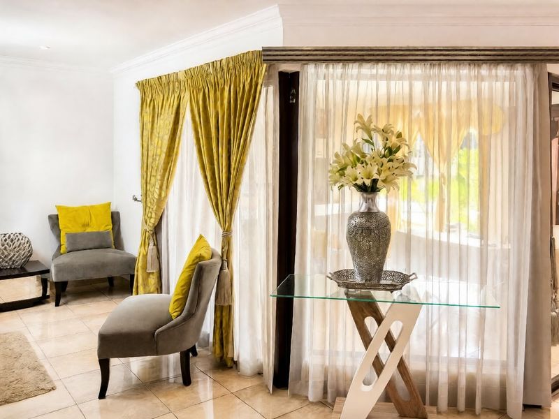 A bright living area featuring tiled flooring, decorative ceiling cornicing, and large glass sliding doors that provide ample natural light.