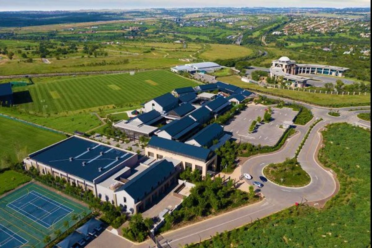 Aerial view of the townhouse complex featuring surrounding sports facilities, tennis courts, and ample parking infrastructure within a landscaped estate setting.