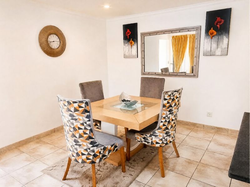 A well-lit dining area featuring neutral tiled flooring and coved ceiling details, providing a functional space for meals.