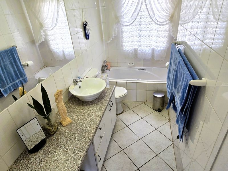 A functional bathroom featuring a vessel sink on a vanity cabinet, a bathtub, and tiled finishes throughout.