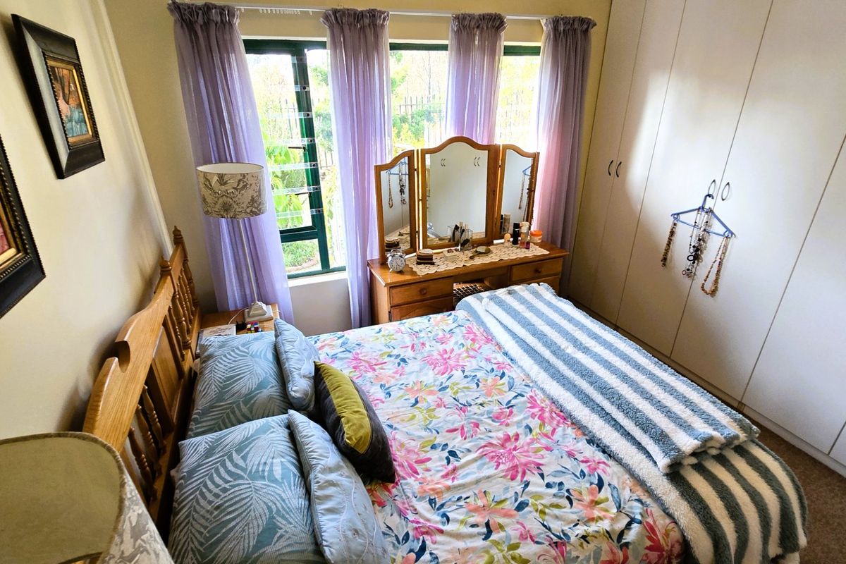 A cozy bedroom featuring built-in cupboards and a large window with natural light, providing a functional and comfortable living space.