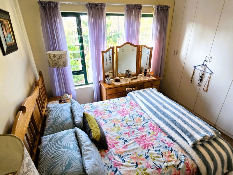 A cozy bedroom featuring built-in cupboards and a large window with natural light, providing a functional and comfortable living space.