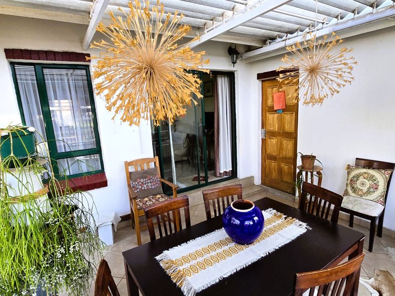 A covered patio area featuring tiled flooring, a corrugated roof, and direct access to the interior through a sliding glass door.