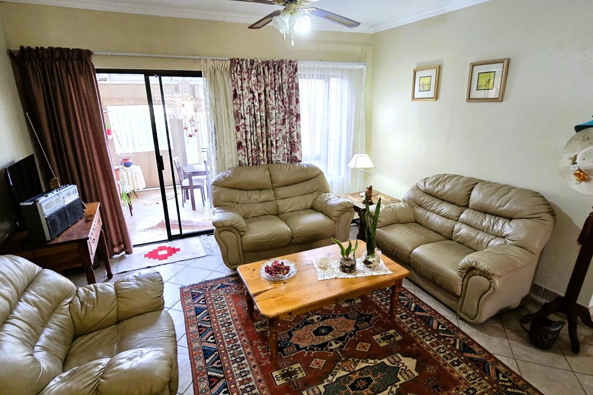 A comfortable living room featuring tiled flooring, a ceiling fan, and large sliding glass doors providing access to an outdoor patio area.