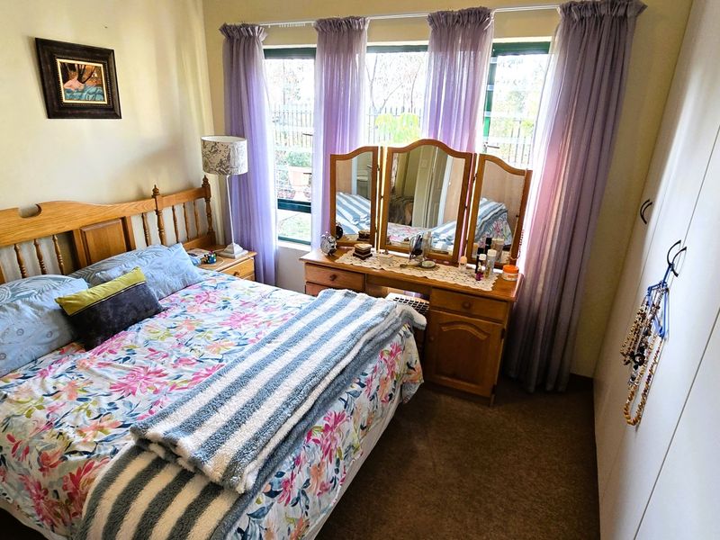 A cozy bedroom featuring a large window with natural light and a built-in wardrobe for storage.