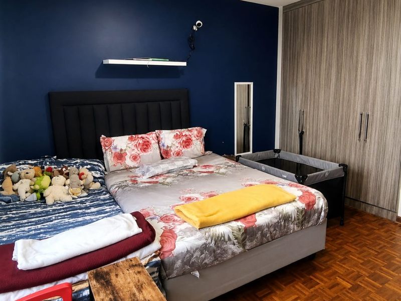 A bedroom featuring dark blue accent wall, built-in wooden cupboards, and classic parquet flooring.