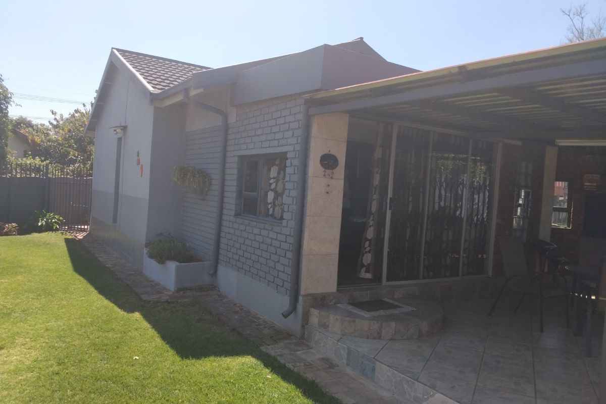 Rear view of the house featuring a covered tiled patio area, brick exterior walls, and sliding glass doors with security gates.