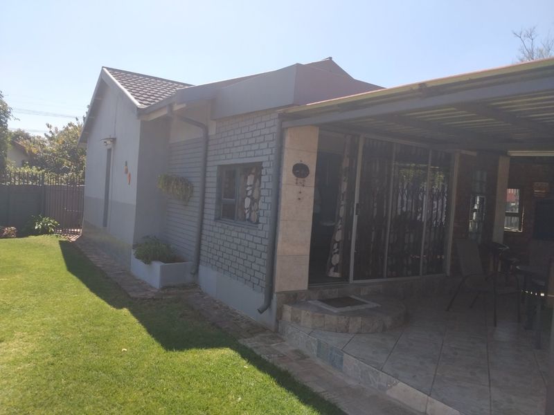 Rear view of the house featuring a covered tiled patio area, brick exterior walls, and sliding glass doors with security gates.