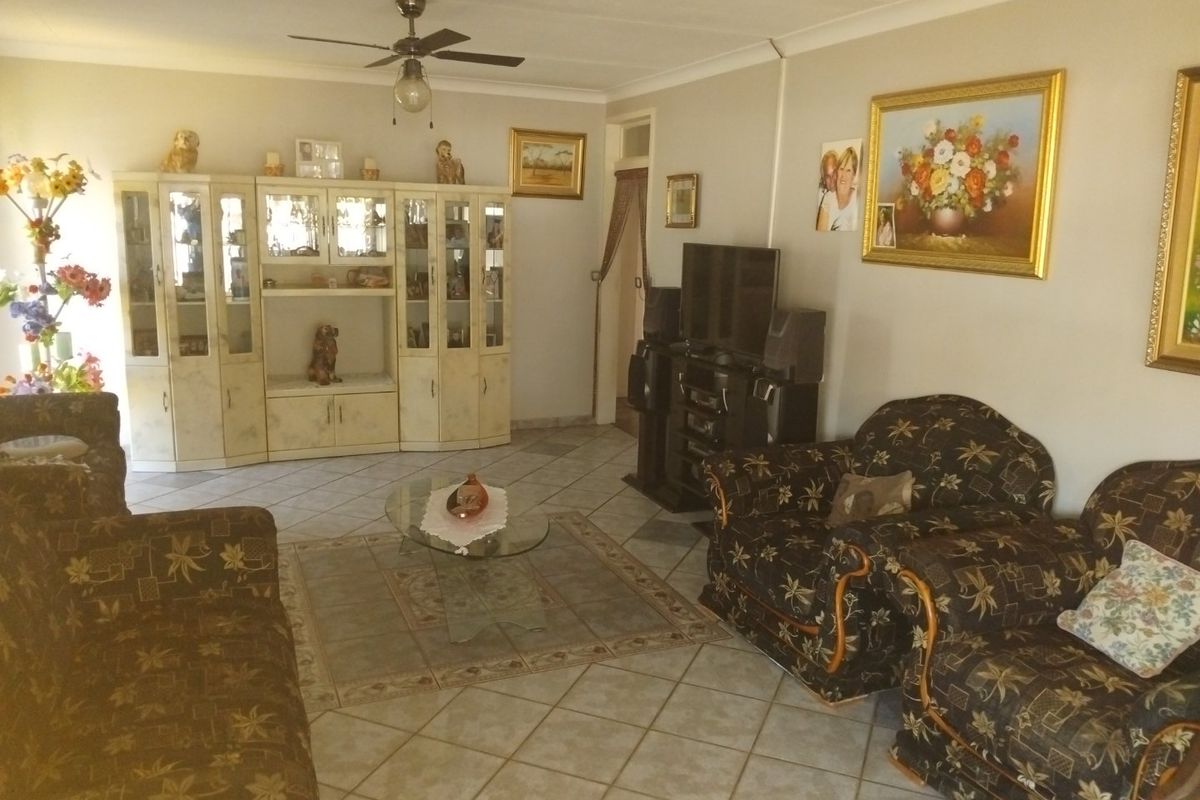 A spacious living room featuring tiled flooring, a ceiling fan, and built-in display cabinetry, offering a functional layout for relaxation.