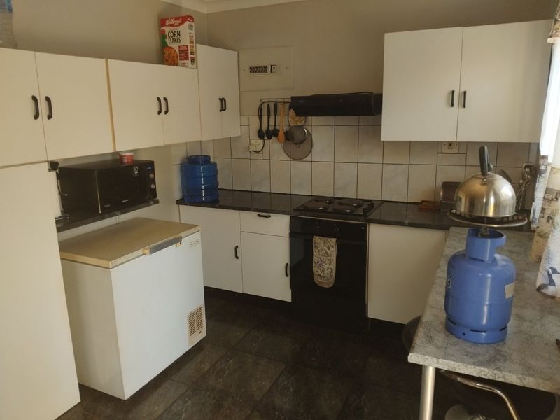Functional kitchen featuring white cabinetry, dark laminate countertops, tiled backsplash, and integrated cooking appliances.